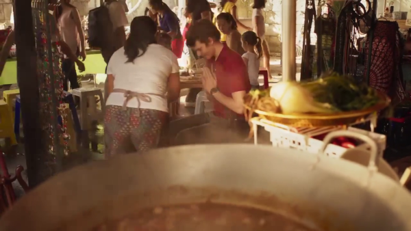 Screen capture from The Bureau of Magical Things, a young man being served soup in a market in Bangkok